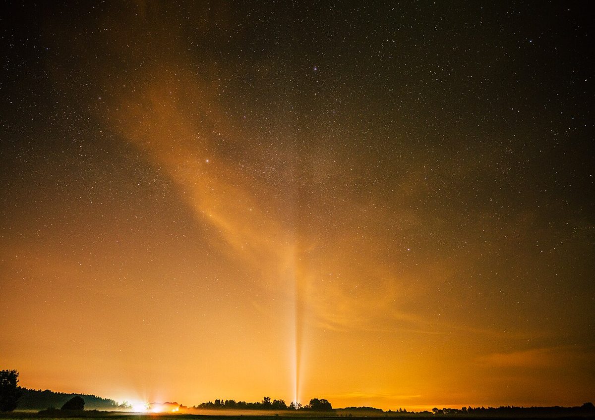 Starry rural sky with a bright dome of light pollution glowing along the horizon